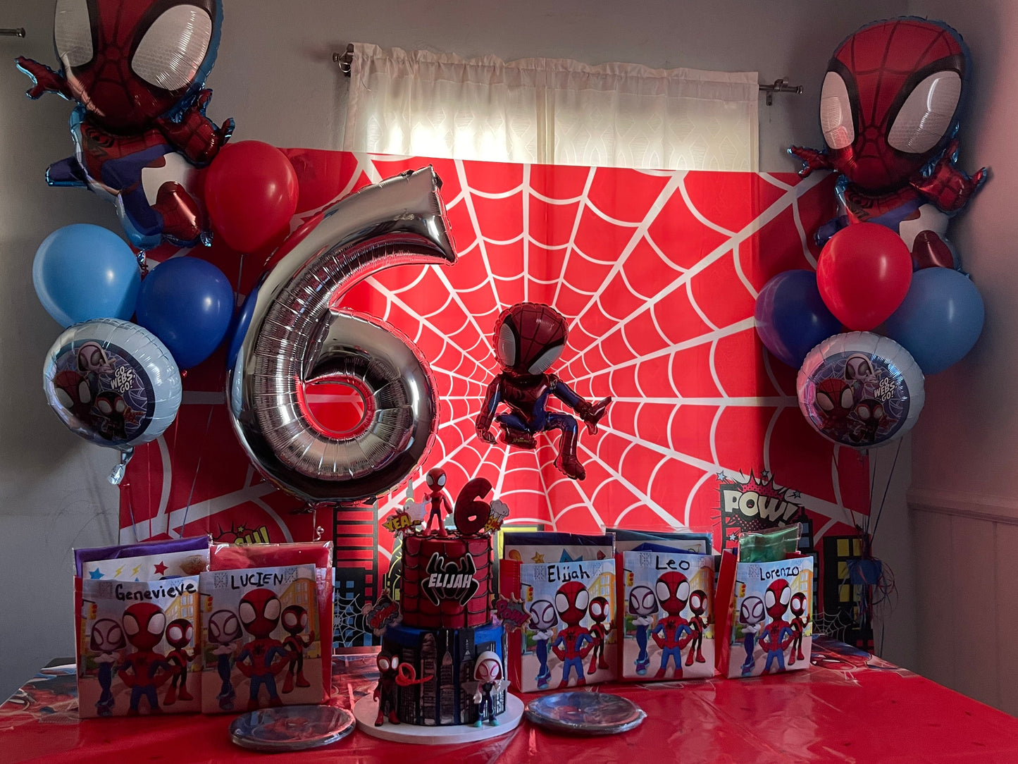 Spider-Man themed birthday party setup with balloons, decorations, and a large number '6' on a table.